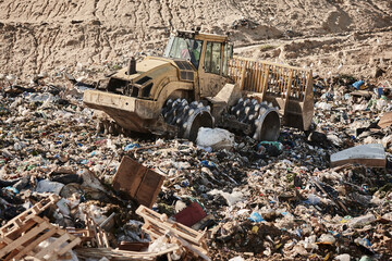 Heavy machinery shredding garbage in an open air landfill. Pollution