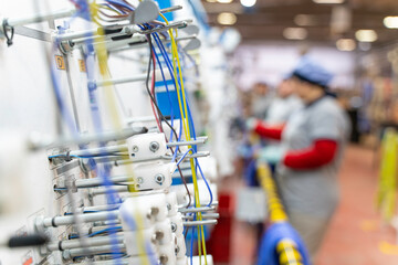 A close up of an electrical wiring line factory harness with a worker in the background.