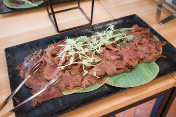 Sliced beef on a black plate in a restaurant