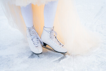 feet of a girl in white ice skates on the ice rink