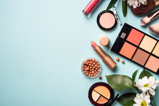 Make up products on blue background. Cream, powder, shadow, brushes. Flat lay image with copy space.