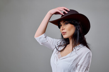 a beautiful brunette woman in a casual outfit with a hat in the studio