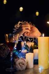 A romantic couple enjoying a candlelit dinner at a restaurant. The table is beautifully set and the dim lighting creates a cozy and intimate ambiance. The focus is on the couple's hands