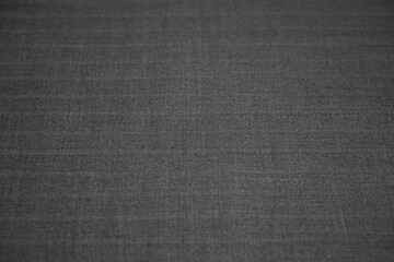 Background of gray fabric with jacquard weave threads. Selective focus. Textural backdrop textile material for graphic and web design in black and white. Shallow depth of field.