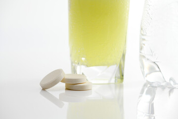 The effervescent tablet dissolves in a glass of water.