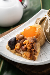 Zongzi. Rice dumpling for Dragon Boat Festival on green leaf background with ingredient.
