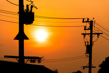 Silhouette electric post on orange sky background