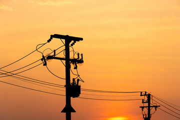Silhouette electric post on orange sky background
