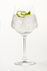 Glass of gin and tonic with lime peel on white background. - obrazy, fototapety, plakaty