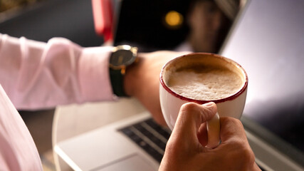 closeup of a man's hand holding a cup of coffee and looking at the time with the other hand