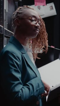 Vertical video: Female police officer reading case information in file, standing in incident room. Private detective using witness statements papers and records to do research, solving criminal