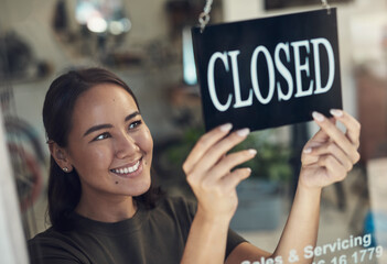 Its been such a rewarding day. Shot of an attractive young woman standing and turning the sign on...