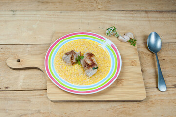 Quirera with pork, garlic and herbs on wooden background.