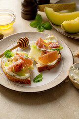 Melon with prosciutto toast with basil and honey. Antipasti snack.