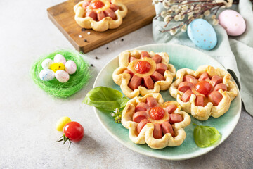 Idea for Easter breakfast or lunch. Mini pizza. Pizza in puff pastry with cheese and tomatoes on the festive table. Copy space.