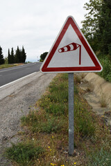Panneau routier : danger aux vents violents.