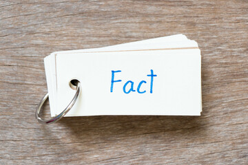 Flash card with handwriting in word fact on wood background