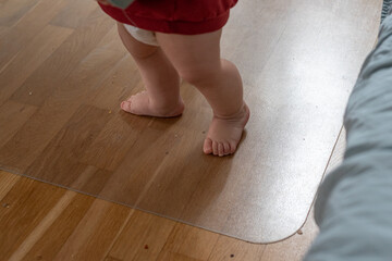 A child stands with bare feet on a wooden floor, legs of a child. Background with space for text.