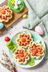 Idea for Easter breakfast or lunch. Mini pizza. Pizza in puff pastry with cheese and tomatoes on the festive table. View from above.