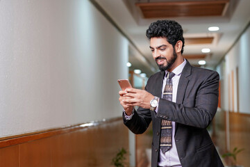 Indian corporate man smiling after looking in smartphone some information.