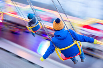 Child, cute boy riding chain swing carousel on sunset, motion blur
