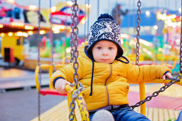 Child, cute boy riding chain swing carousel on sunset, motion blur