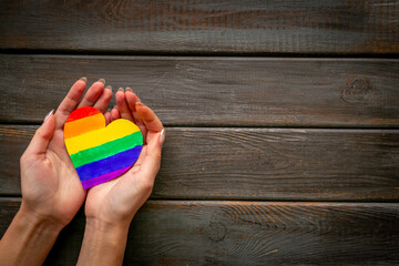 Female hands with rainbow LGBT colored heart paper cut. LGBT social rights concept.
