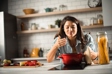 Beautiful pregnant woman preparing delicious food. Smiling woman cooking pasta at home