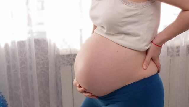 Closeup of pregnant woman's belly, problems with spine, ache symptoms