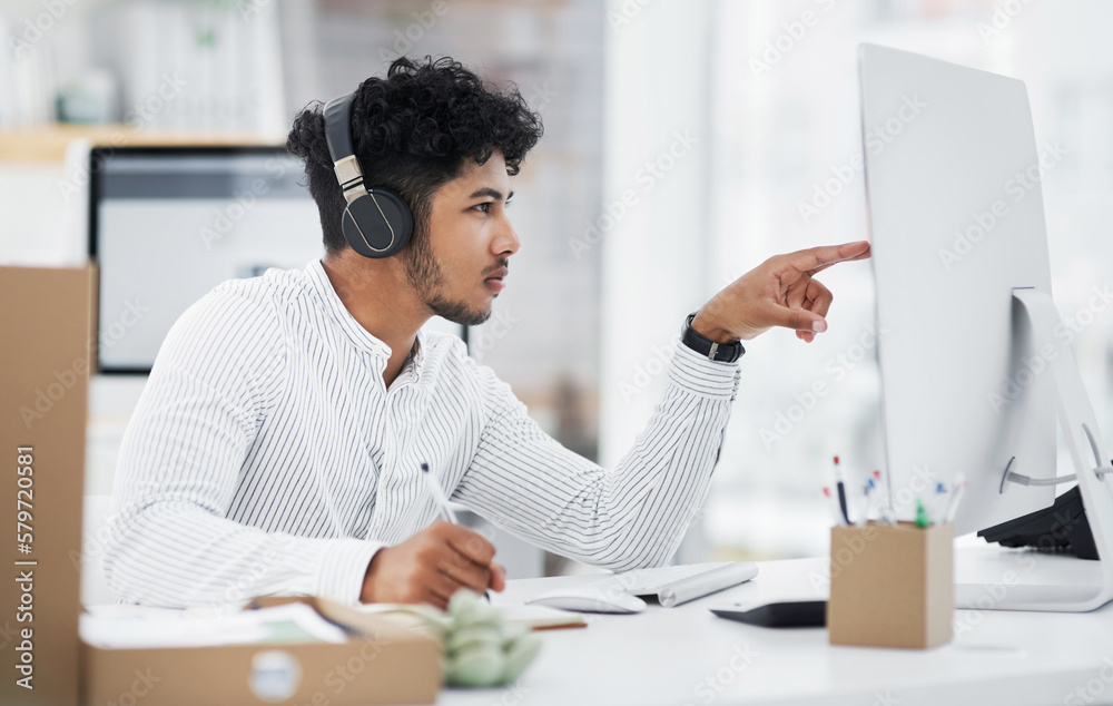 Poster i better read through this carefully. shot of a young businessman wearing headphones while working o
