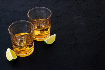 Glass of whiskey with lime and ice. Strong alcohol background