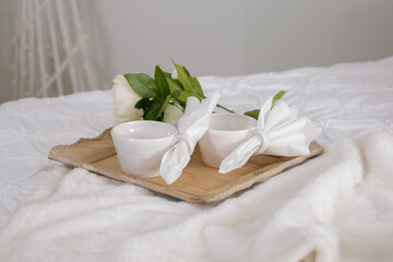 Fototapeta na wymiar Cup of tea with white flowers on a wooden tray on the bed