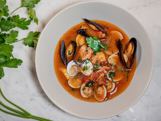 Mediterranean fish soup with mussels, clams, prawns, tomato. fish soup served on white dish.