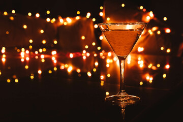 A glass of dirty martini without olives, with blurred background light, and bokeh on a night club bar counter 