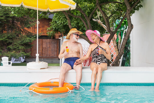 Happy senior women relaxing and sunbathing in the swimming pool during summertime - Cheerful elderly people having fun at a pool party - Powered by Adobe