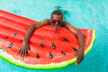 Happy black senior man swimming and having fun  in the swimming pool, relaxing day during summertime