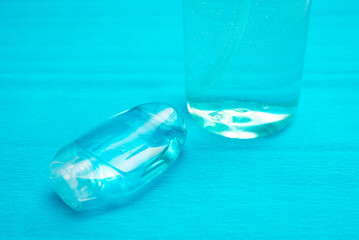 Plastic bottle of the blue transparent liquid soap and a pocket antiseptic gel isolated over the blue background 
