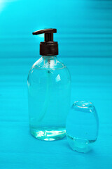 Plastic bottle of the blue transparent liquid soap and a pocket antiseptic gel isolated over the blue background 