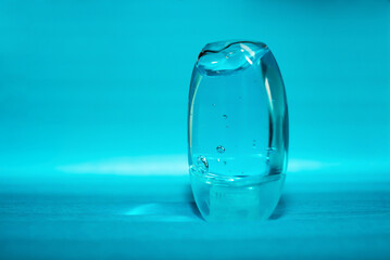 Pocket antiseptic hand sanitizer gel isolated on blue  background, no label. Small bottle of transparent blue antibacterial liquid with oxygen bubbles, round granules. Hydro alcoholic, ethyl alcohol. 