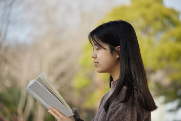 春の公園で読書している女子中学生の姿