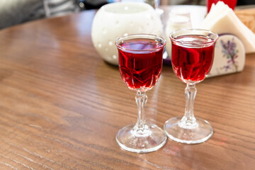 Two glasses of cranberry tincture stand on the wooden table, close up