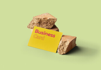 Mockup of customizable horizontal color business card resting against rocks available against customizable color background