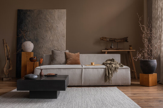 Interior design of wabi sabi living room interior with mock up poster frame, modular sofa, gray rug, vase with branch, bench, wooden sculpture and personal accessories. Home decor. Template.
