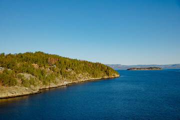 Obraz premium Norwegian fjord with trees and small houses. North Sea in Norway.