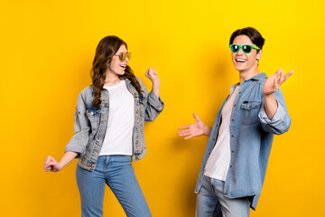 Portrait of two carefree overjoyed people enjoy dancing partying isolated on yellow color background