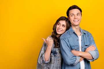 Fototapeta premium Photo of two cheerful people folded hands look indicate finger empty space isolated on yellow color background
