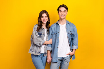Fototapeta premium Photo of two positive cheerful people hold arms toothy smile isolated on yellow color background