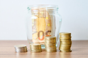 Coins in a glass jar on the table with white background
