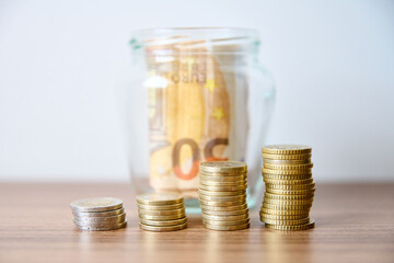 Coins in a glass jar on the table with white background