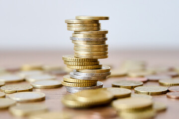 Pile of coins on a wooden table with shallow depth of field